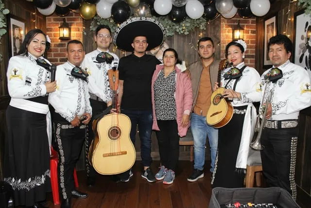 Mariachi con traje blanco y negro en cumpleaños de joven con mamá y hermano en casa Bogotá